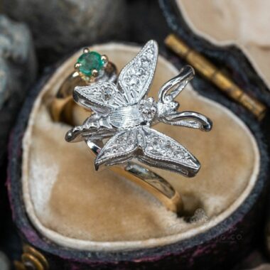 A close-up view of a whimsical butterfly ring with intricate silver wings and colorful gemstone accents.